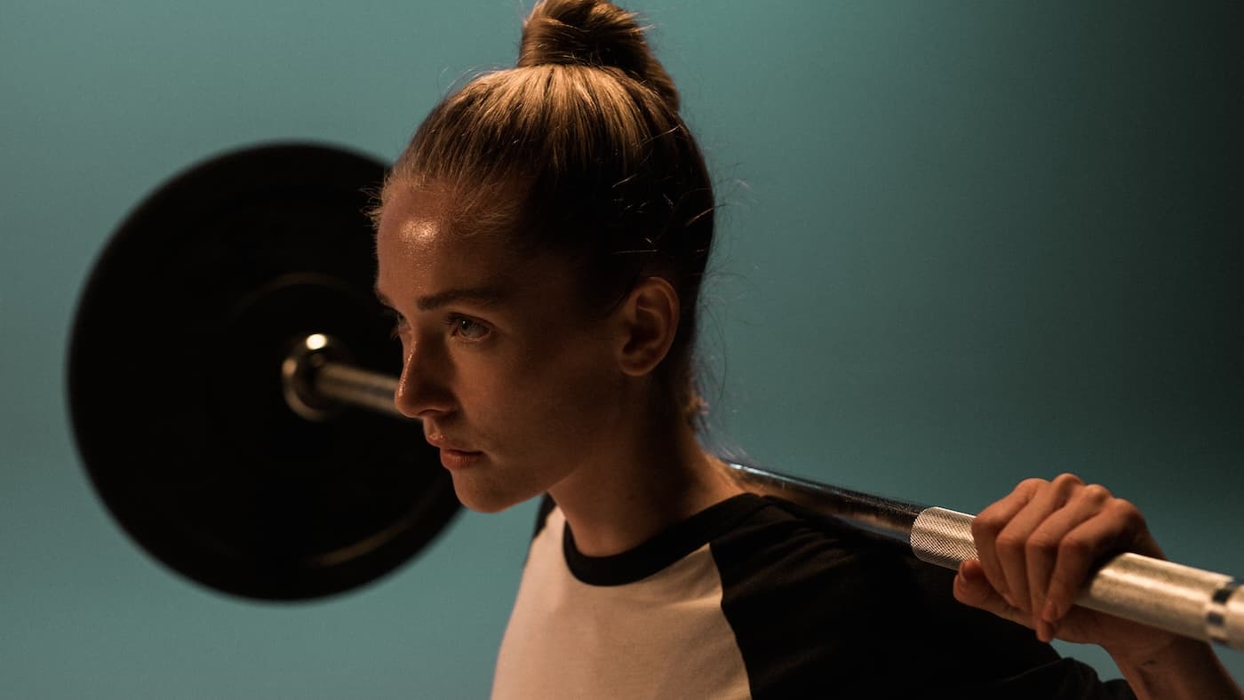 Vrouw in fitnessruimte met barbell op haar nek om te squatten